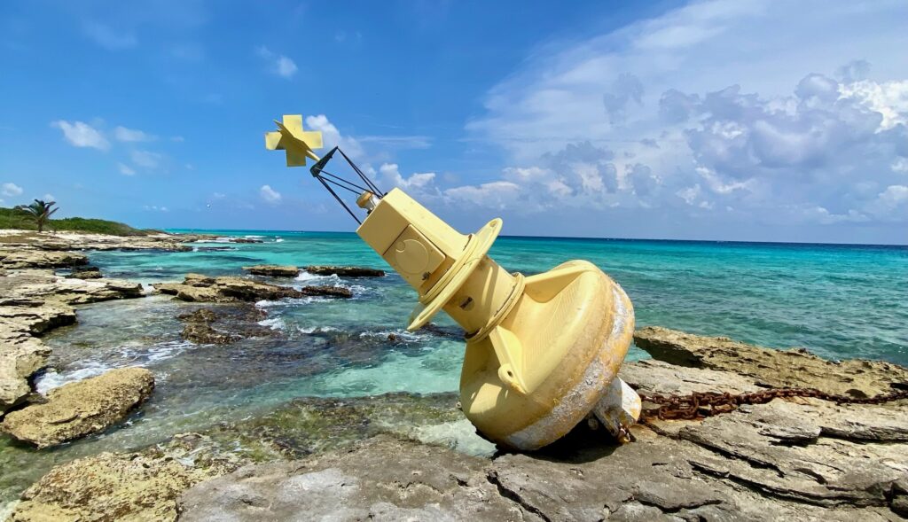 Riesige gelbe Boje am steinigen Karibikstrand bei PDC