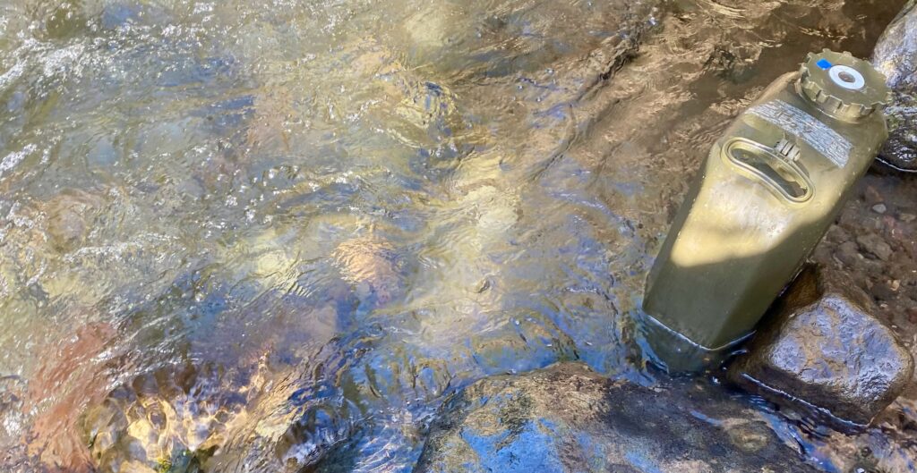 Wasserkanister im Fluss auffüllen